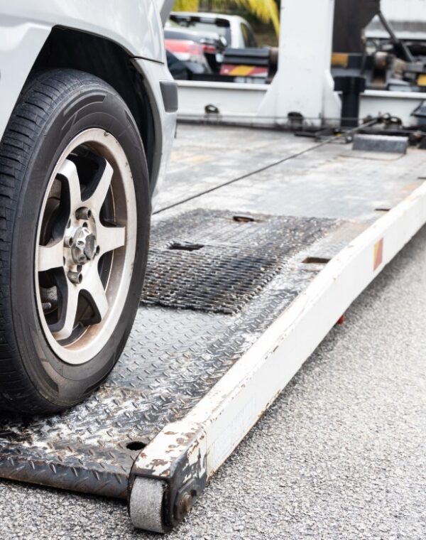 Cable attached to broken down car being pulled onto flatbed tow truck