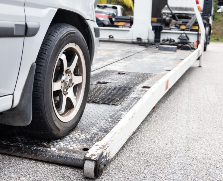 Cable attached to broken down car being pulled onto flatbed tow truck