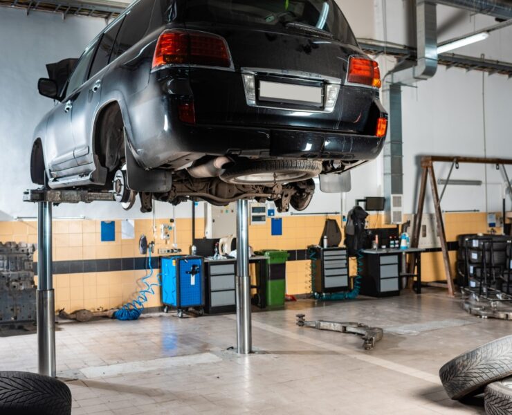 modern black car raised on car lift in workshop